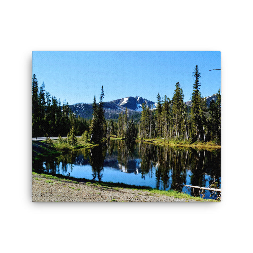landscape of a reflective lake with evergreen trees and mountain background