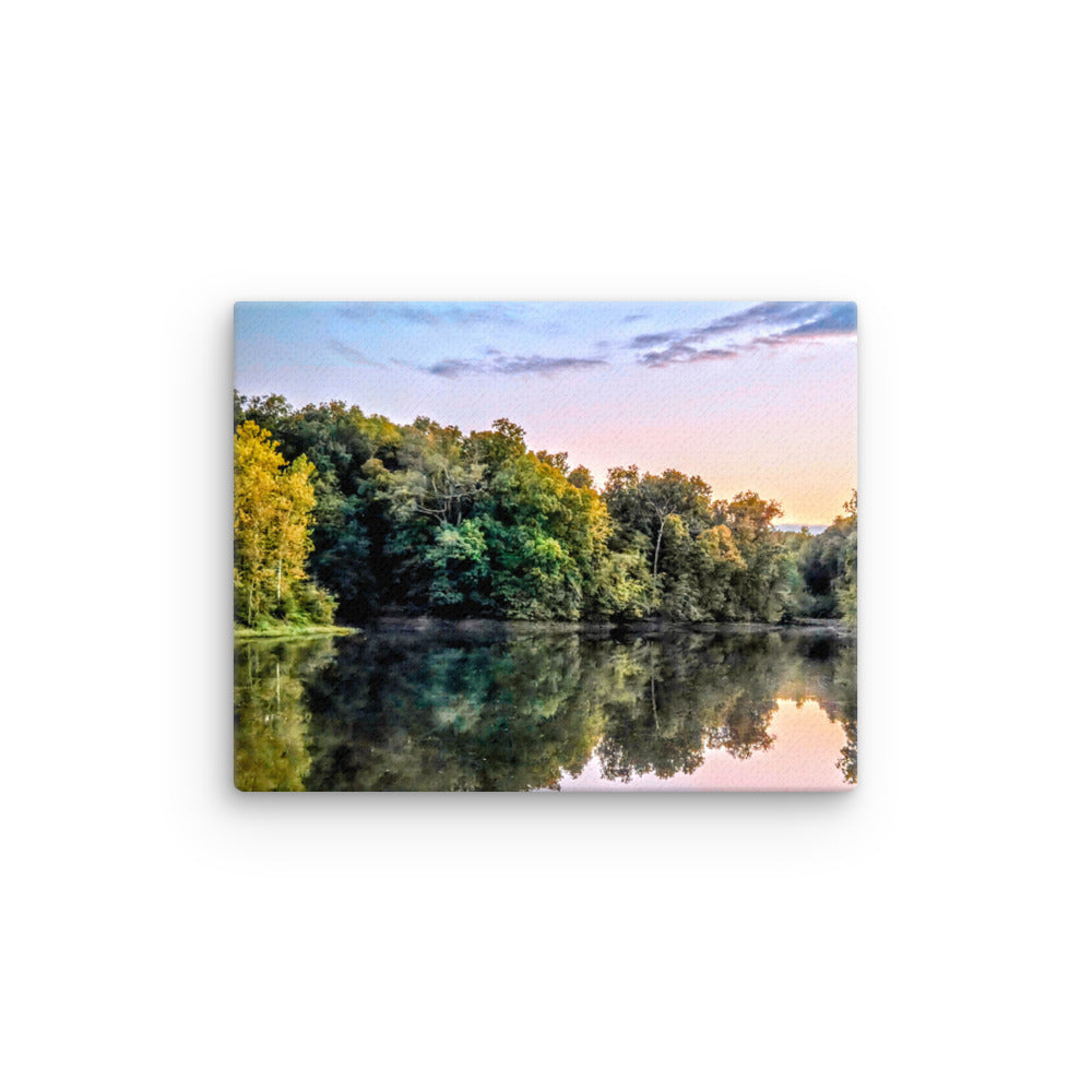 Lake surrounded by trees with a sunset reflection on the water