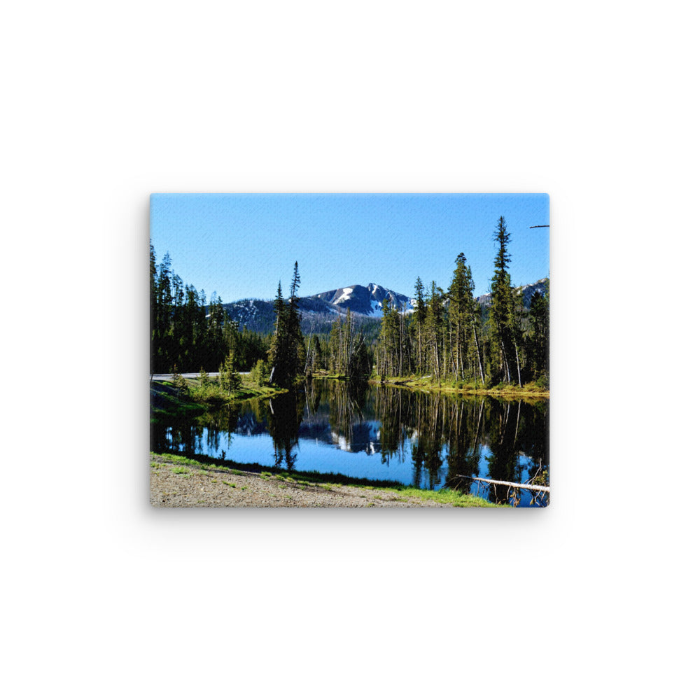 landscape of a reflective lake with evergreen trees and mountain background