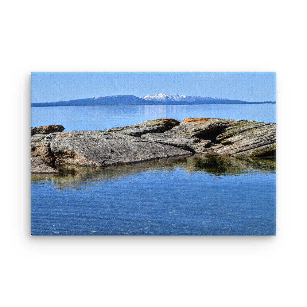 Rocks in a blue lake with a mountain in the background