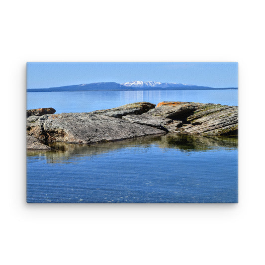 Rocks in a blue lake with a mountain in the background