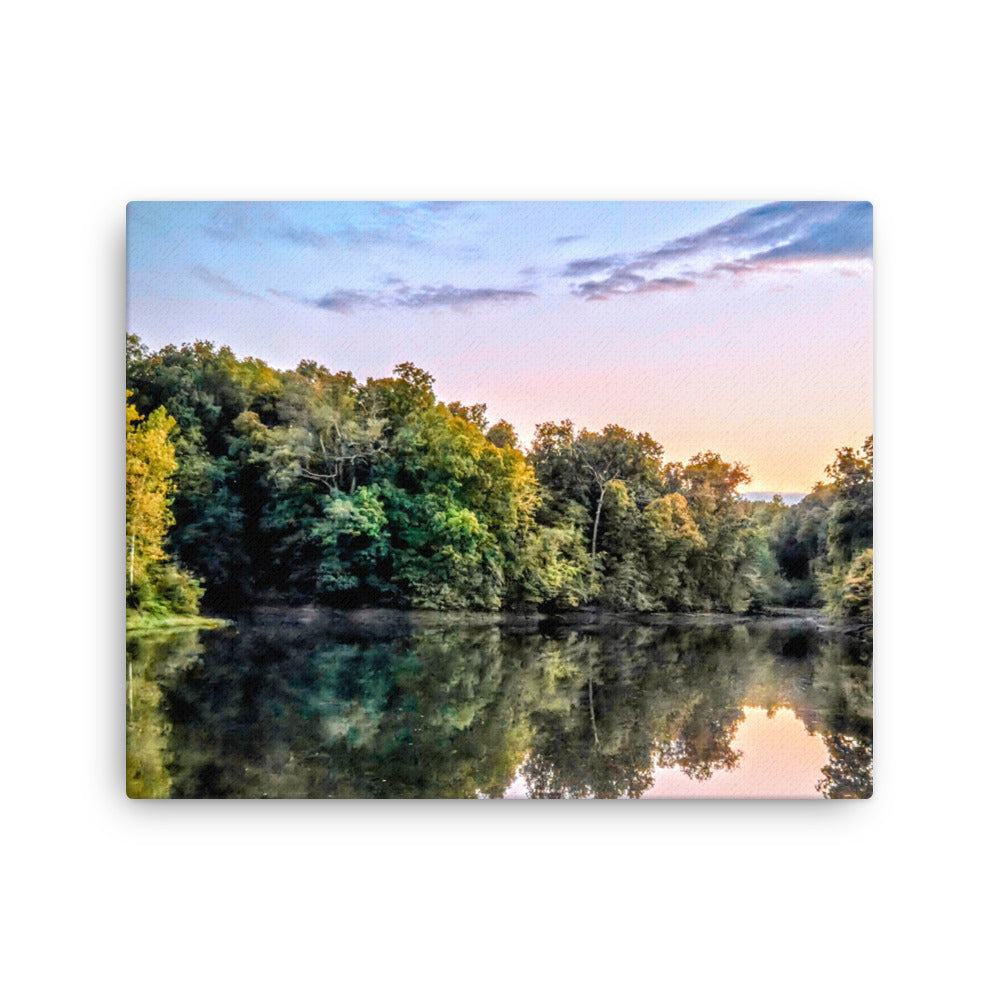 Lake surrounded by trees with a sunset reflection on the water
